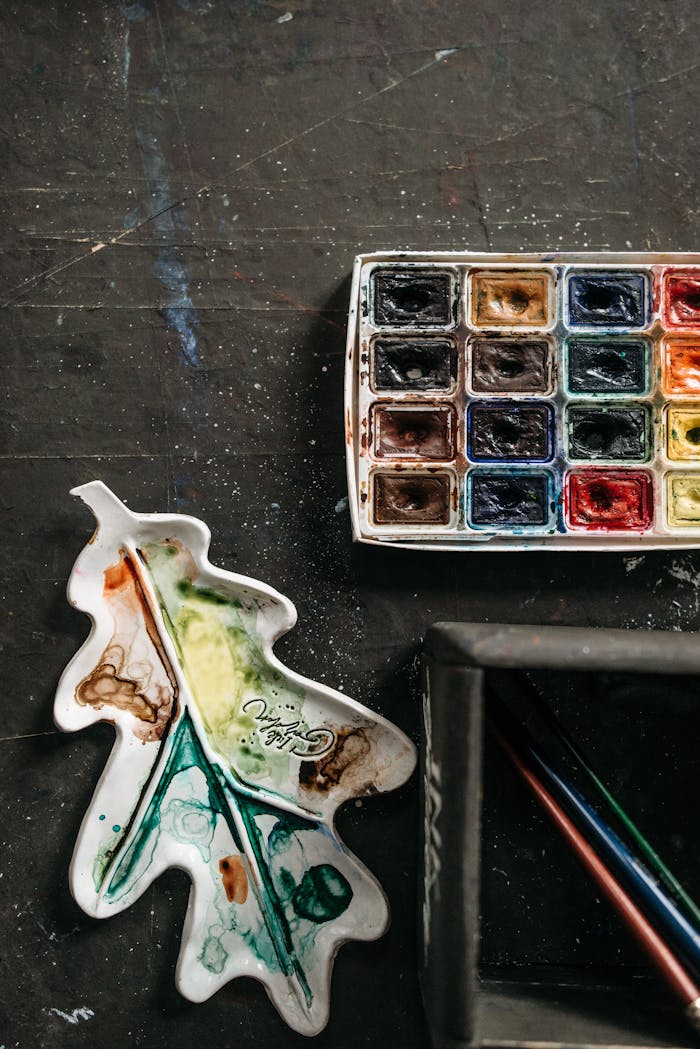 A colorful watercolor set and palette arranged artistically on a dark table, ideal for creative projects.